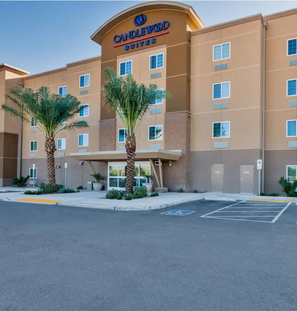 A parking lot with palm trees and a building.