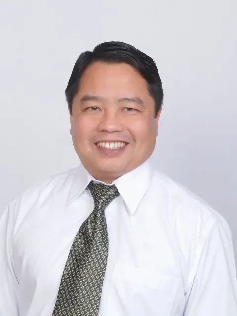 A man in white shirt and tie smiling for the camera.