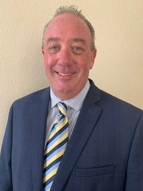 A man in a suit and tie standing next to a wall.