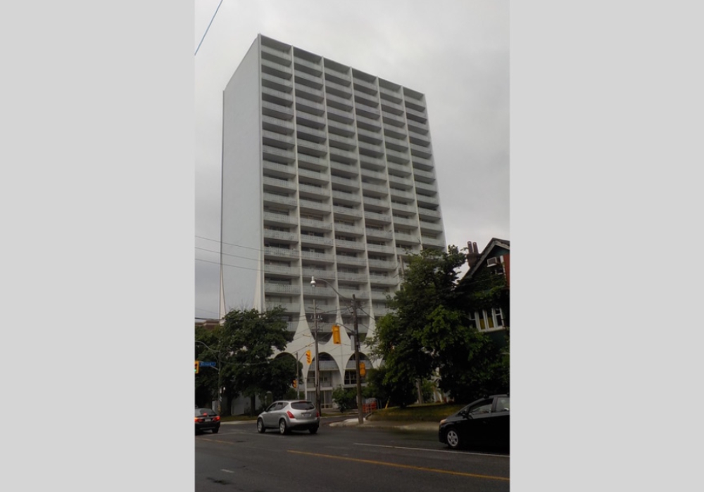 A tall white building with cars driving down the street.